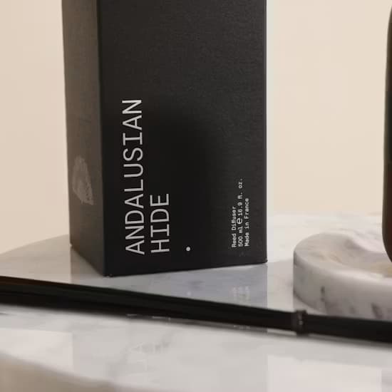 Sleek modern glass vessel of Andalusian Hide diffuser on a stylized display shelf
